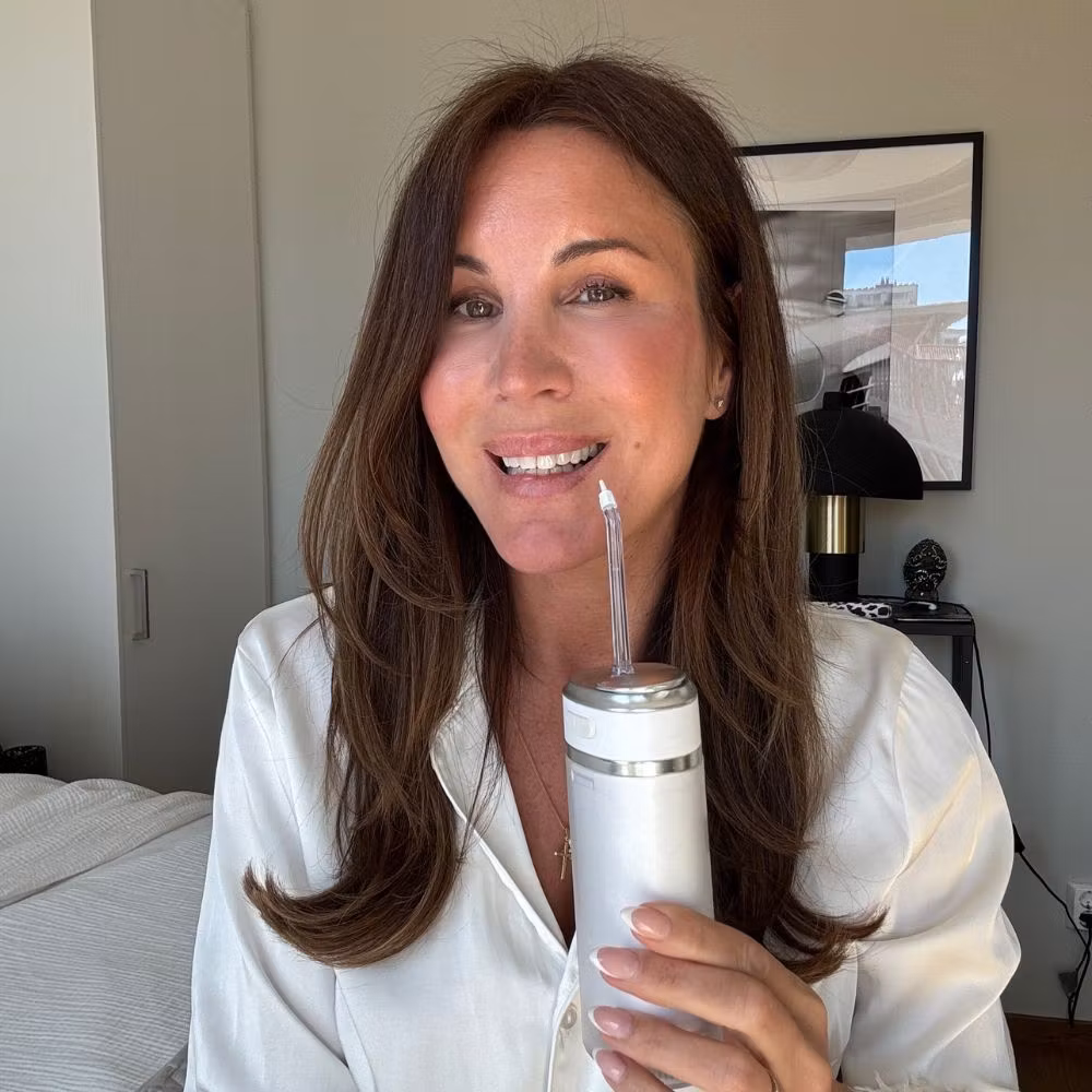 A woman holding the Waterflosser Pro at home